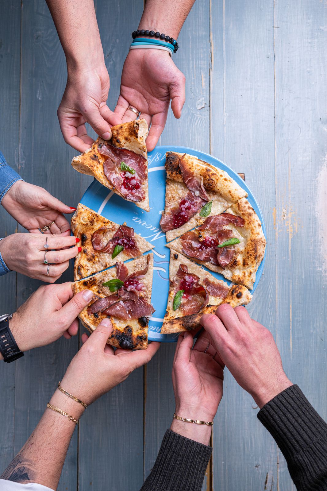 Mani che prendono le fette dalla stessa pizza