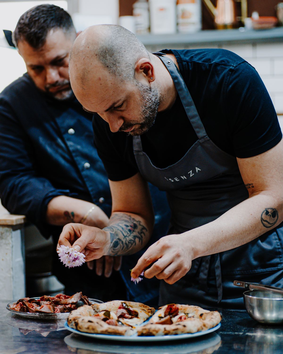 Due pizzaioli al lavoro sullo stesso piatto